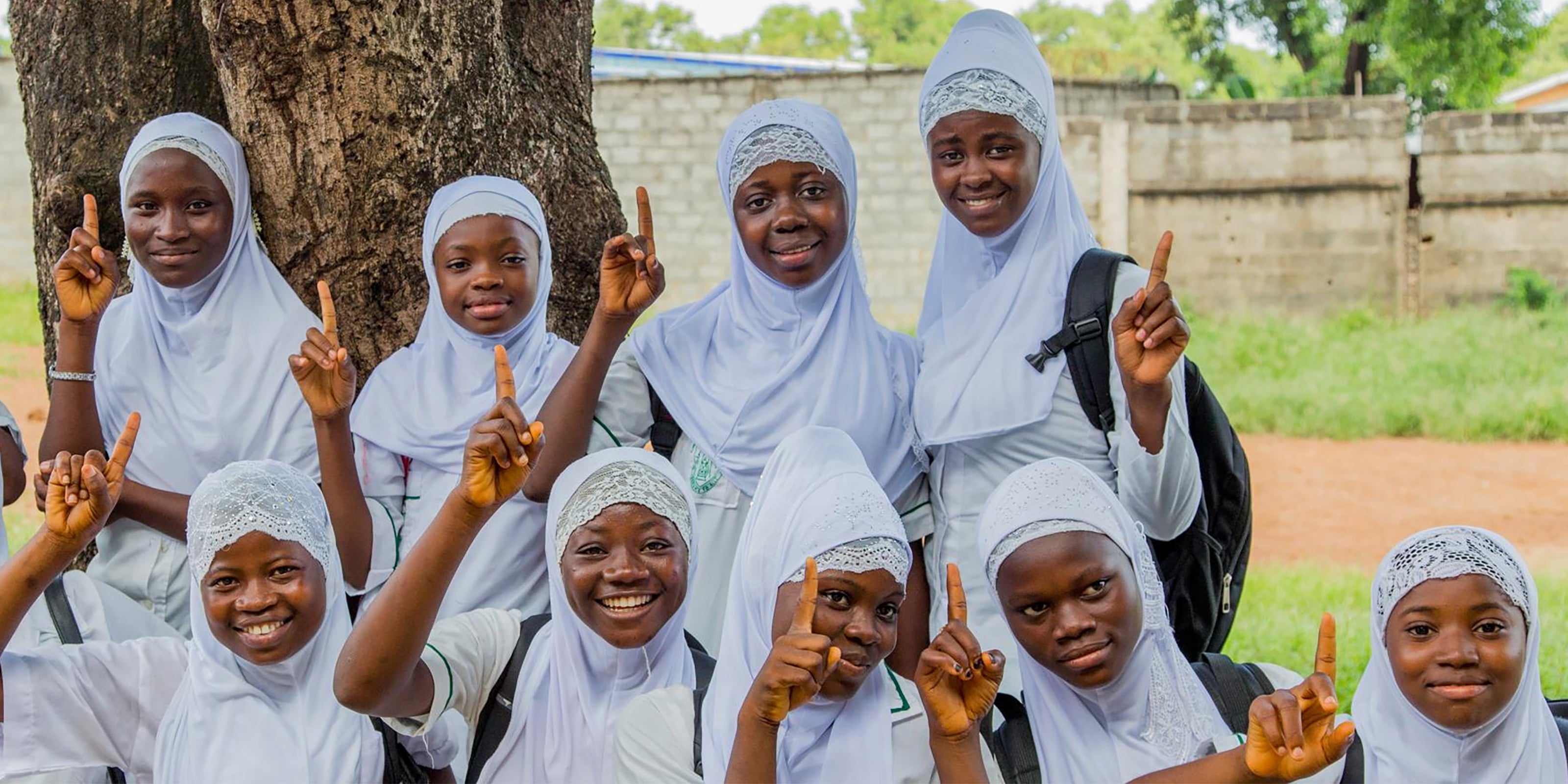Girls being helped by ONEGIRL with their index finger raised