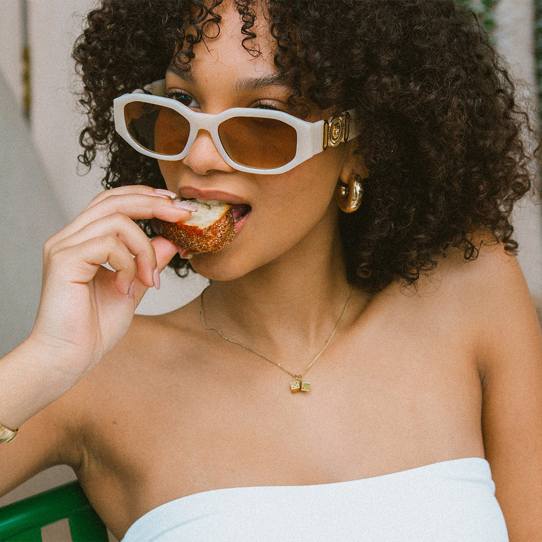 Vogue Cream Angular Womens Sunglasses made of polycarbonate and brown lens on female model eating bread while looking side on away from the camera