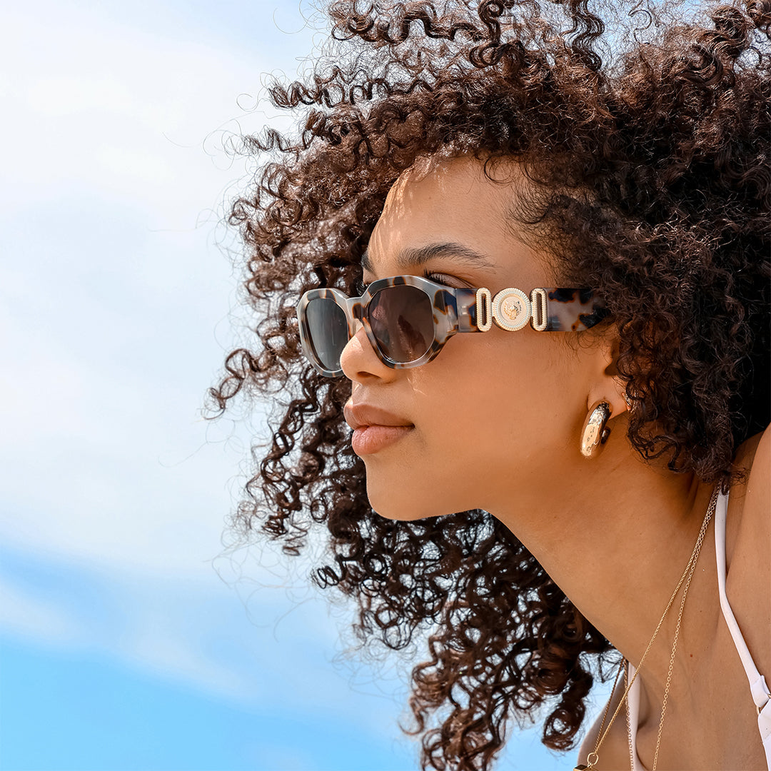 Vogue Tort Angular Womens Sunglasses made of polycarbonate and G15 lens on a female model looking sideways from the camera