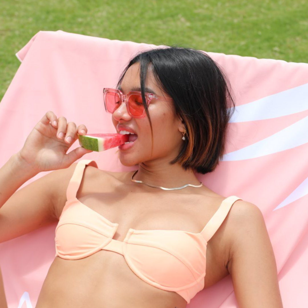 Female model wearing The Weekender - Pink Pink while eating a watermelon